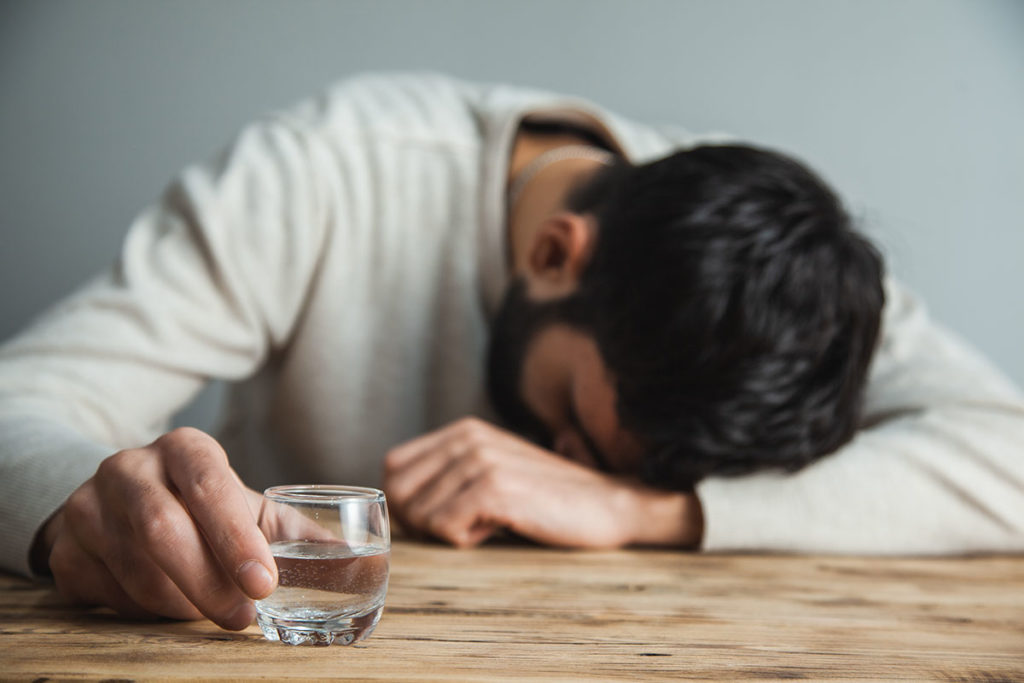 man passed out holding shot of alcohol showing alcohol and depression