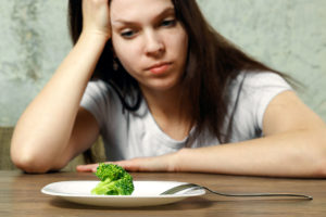 woman glaring at broccoli drug abuse and eating disorders