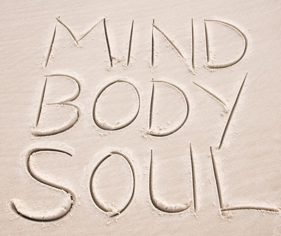 Writing in sand that says "Mind, Body and Soul" stacked on each other