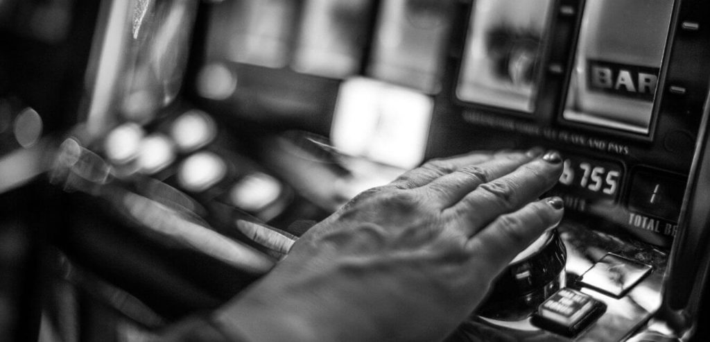 Black and white photo of a hand on a slot machine