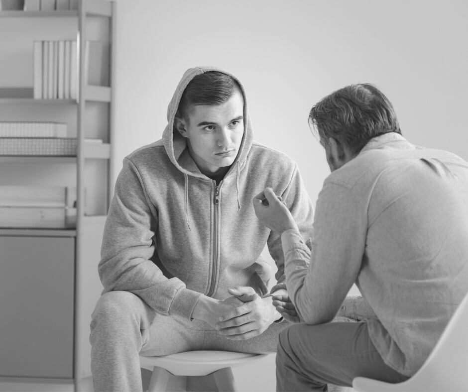 A young man being spoken to by his counsellor