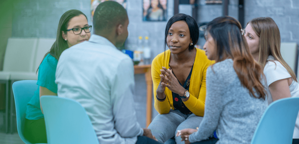 A group of women sitting and a male who looks depressed giving him comfort and some advice