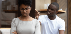 A black male is angry and scolds while pointing his finger to his female partner inside their household