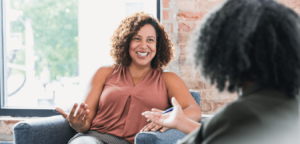 Woman with natural hair sitting on couch talking to female therapist