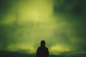 person standing under green aurora borealis, wondering what is addiction