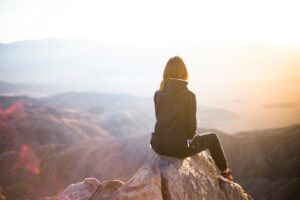 person sitting on top of gray rock overlooking mountain during daytime, mental health iop