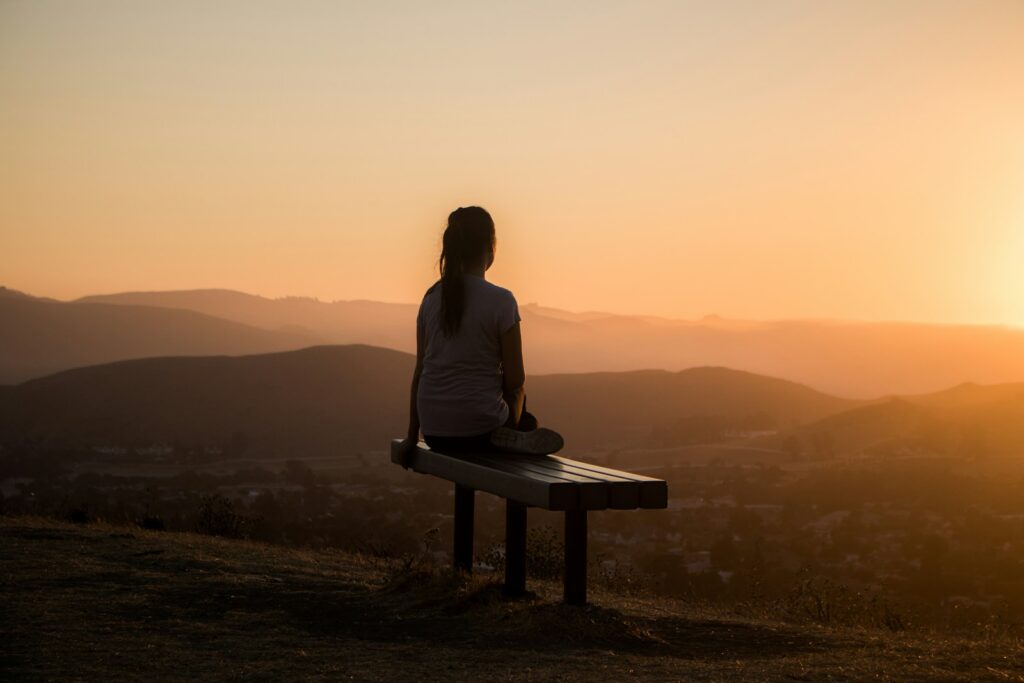 woman sitting on bench over viewing mountain. substance abuse recovery