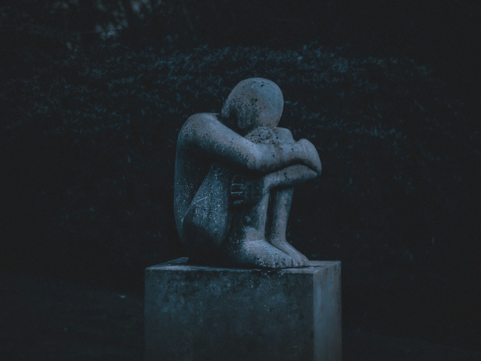 man hugging his knee statue, mental health retreat for grief and loss