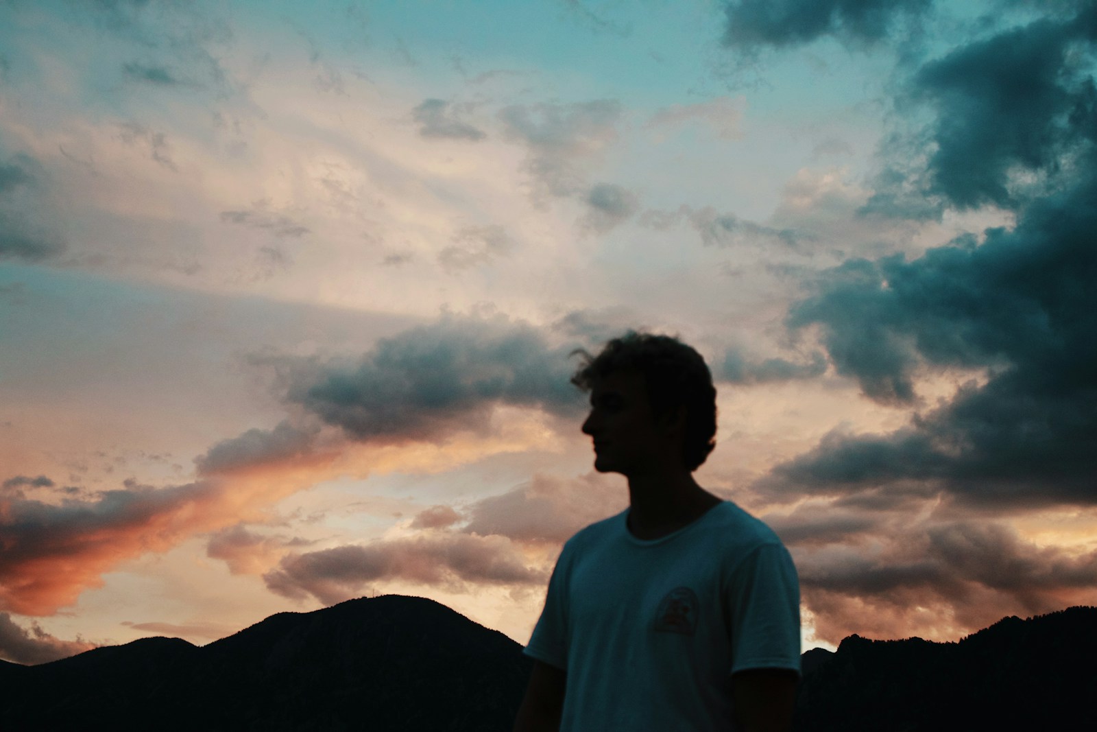 man in white crew neck t-shirt standing on mountain under white clouds during daytime struggling with arousal addiction