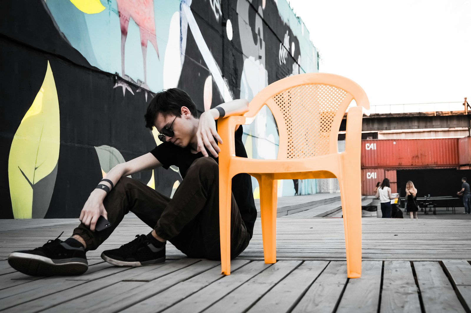 man with cocaine withdrawal symptoms sitting on floor beside empty orange plastic monobloc armchair at daytime