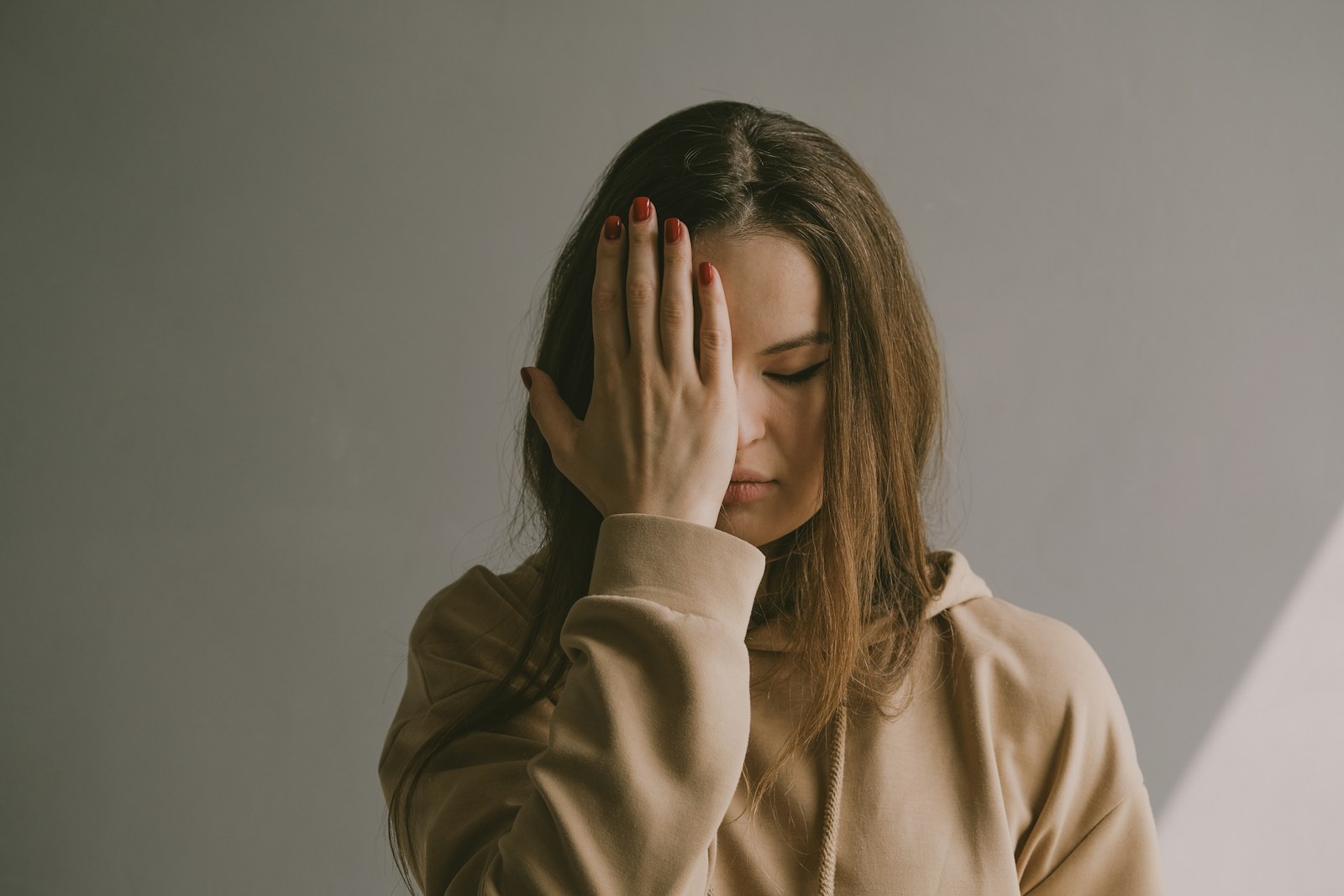 a woman covering her face with her hands, adults with traumatic childhood