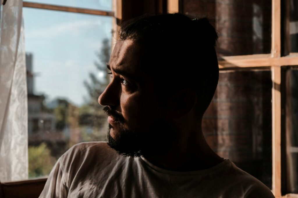 a man looking out of a window in a building considering heroin rehab