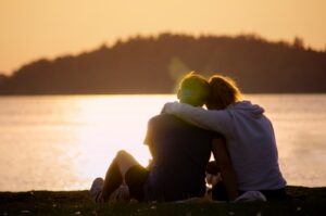 couple with love addiction symptoms sitting on green grass field near body of water during daytime