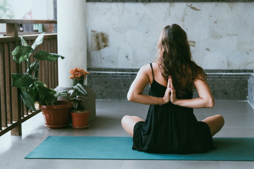 woman wearing black shirt sitting on green yoga mat, trauma informed yoga