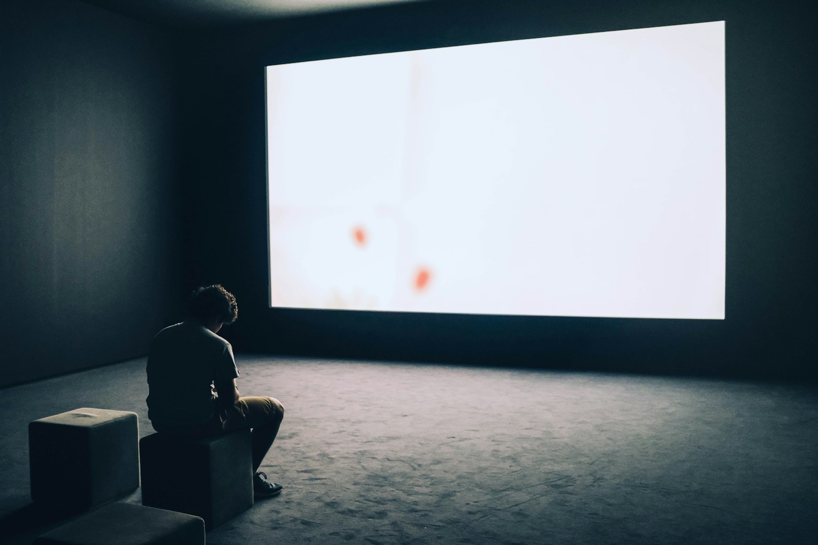 man struggling with porn addiction symptoms sits in front projector screen