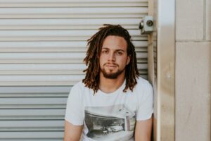 man sitting near gray steel roller shutters during daytime struggling with chronic masturbation