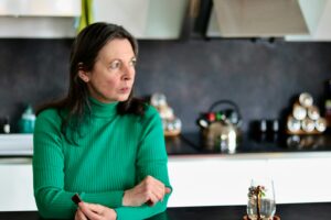 a woman sitting at a table in a kitchen worried about the signs of opioid overdose in a loved one