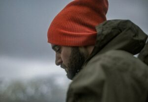 man wearing gray hoodie and orange knit cap thinking about porn addiction statistics