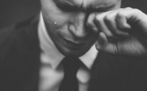 man wiping his tears, struggling with being addicted to sex