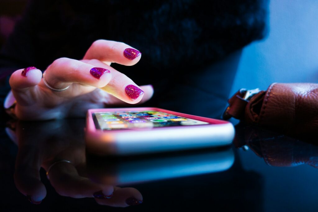 person using black smartphone with gray and pink case to look up mental health apps