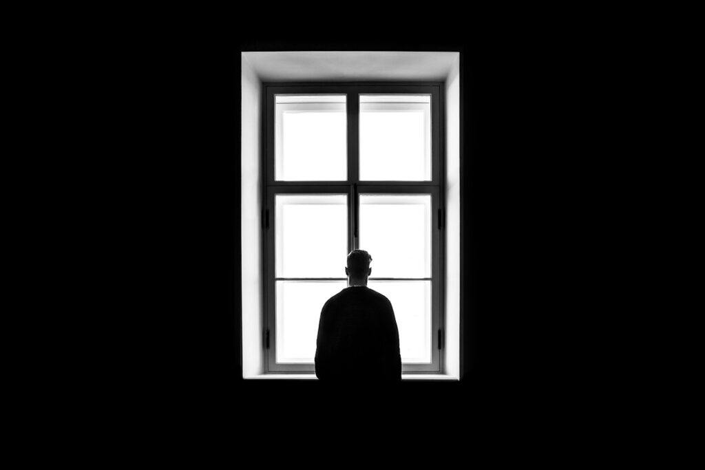 man standing in front of the window wondering what causes sex addiction