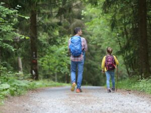 man trauma-informed parenting in blue jacket and blue denim jeans walking on dirt road during daytime