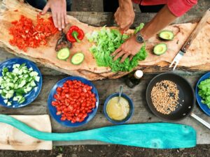 person slicing green vegetable in front of round ceramic plates with assorted sliced vegetables during daytime, practicing self soothing techniques