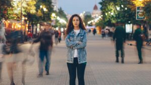 Woman in love addiction treatment stands still amid a busy city street