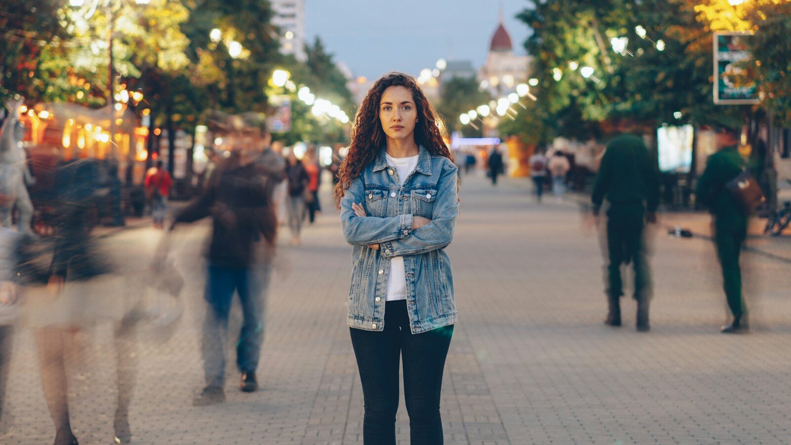 Woman in love addiction treatment stands still amid a busy city street