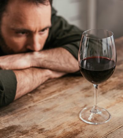 man staring down glass of wine wondering am I an alcoholic